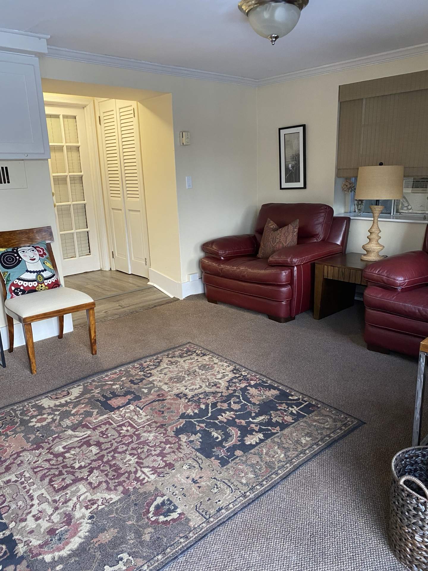Living area with leather chairs, historic fireplace mantel, and oriental rug at The Phillips Mansion