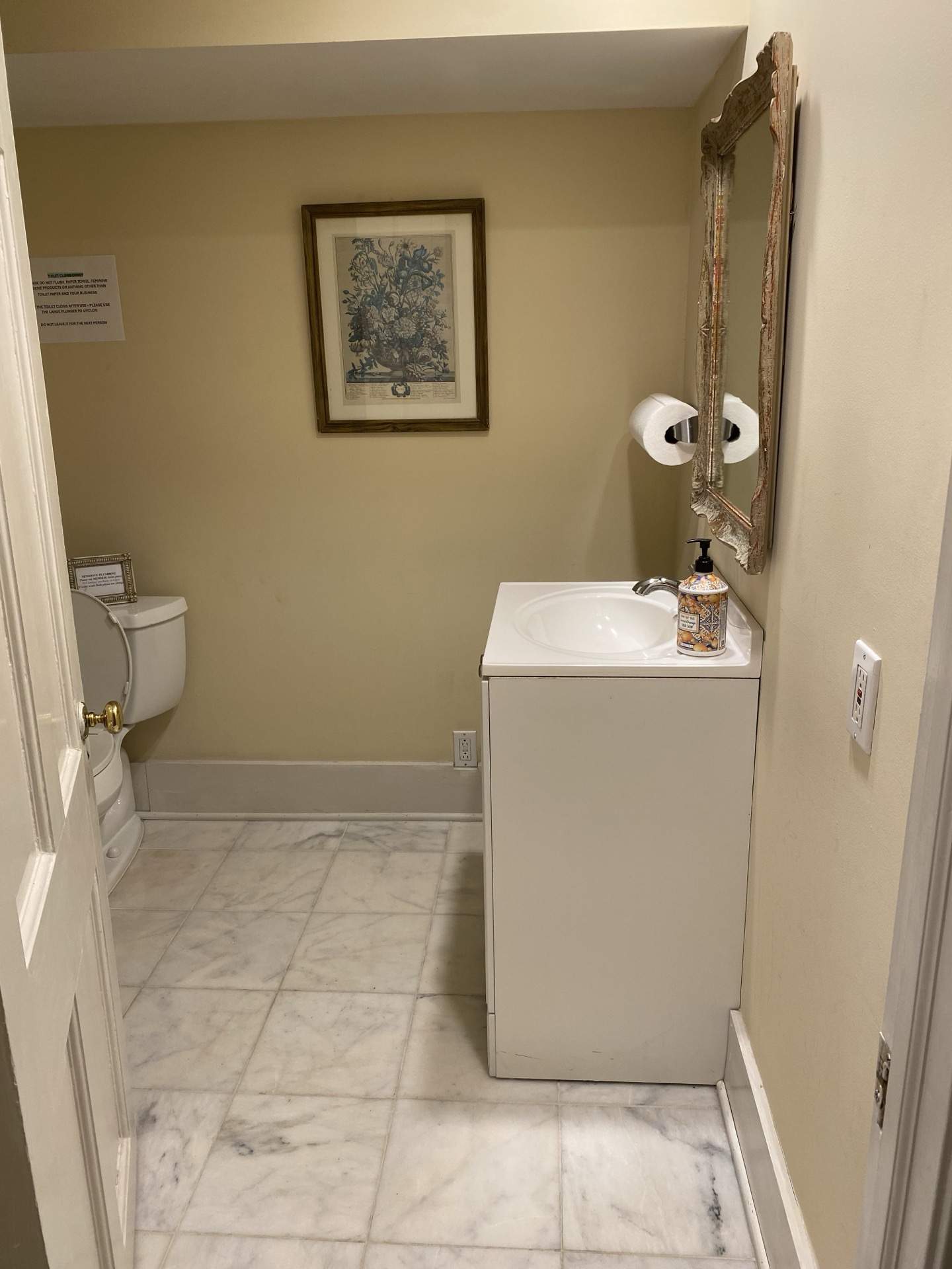 Bathroom with marble tile, pedestal sink, and framed artwork at The Phillips Mansion