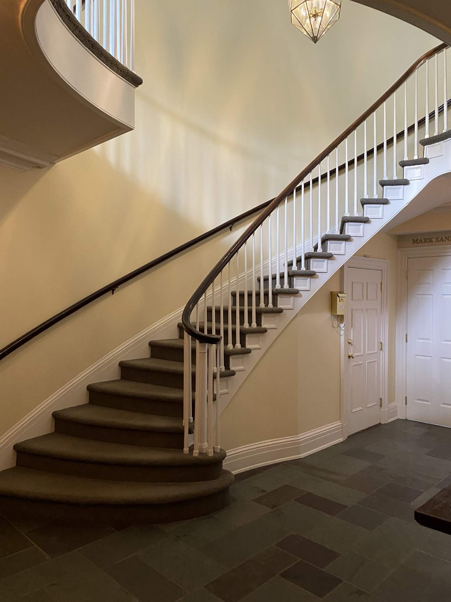 Grand curved staircase with carpeted runner and dark wood banister at The Phillips Mansion